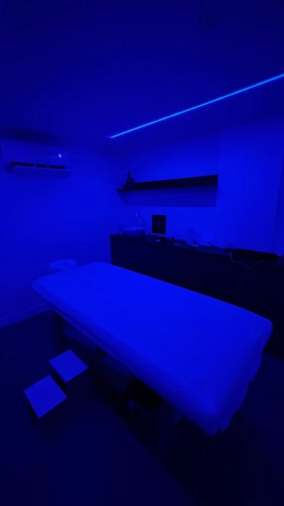 Sala de massagem com maca e iluminação azul