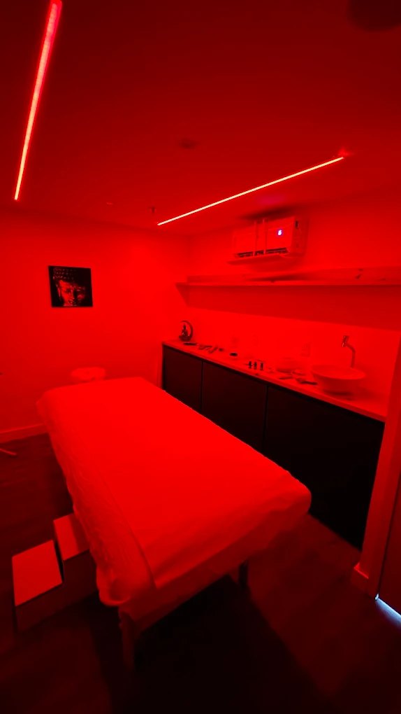 Sala de massagem com maca e iluminação vermelha